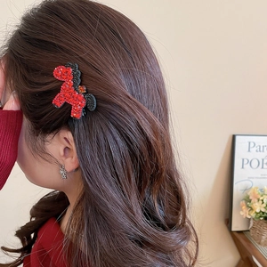 Close-up of a red rhinestone pony hair clip with beaded accents on a female model