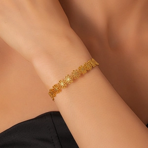 Detailed shot of a gold open cuff bracelet with hollow floral daisy chain on wrist