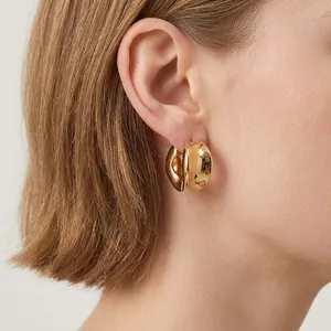 Minimalist thick golden hoop earrings with mirror polish finish on model's ear