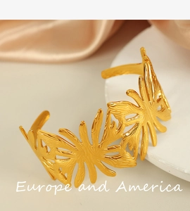 Detailed view of a gold-tone steel bracelet with hollowed leaf patterns on silk