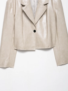 Detail der hellbeigen PU-Lederjacke mit markantem Revers und einem schwarzen Knopf