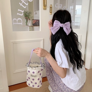 Close-up of lavender silk bow accessory and purple polka dot bucket bag with wavy trim