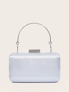 Close-up of silver satin evening clutch with sparkling rhinestone clasp and round metal handle