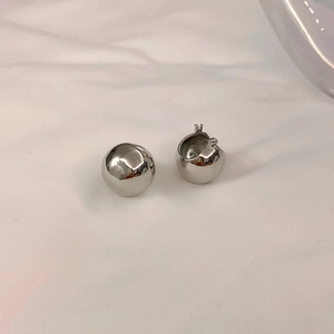 Macro shot of minimalist silver ball earrings with a mirror-like metallic finish