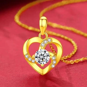 Detailed view of a gold heart pendant with a central diamond on a red textured background