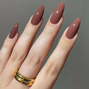Close-up of glossy almond clay-red press-on nails with minimalist gold double-ring