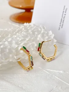Detail of gold titanium hexagon hoop earrings with colorful inlaid cubic zirconia
