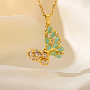 Elegant gold butterfly necklace with green gems and zircons on silk background