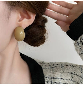 Gros plan d'une boucle d'oreille ovale en résine verte portée par un mannequin