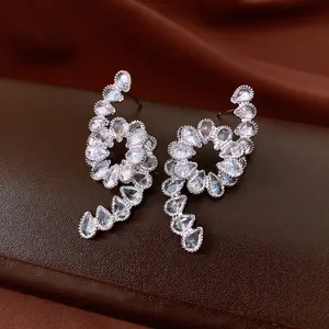 Sparkling silver spiral drop earrings with pear-cut zircon on brown leather jewelry box