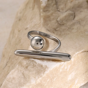 Detailansicht eines geometrischen Stahlrings mit Silberperle und Stab auf Stein
