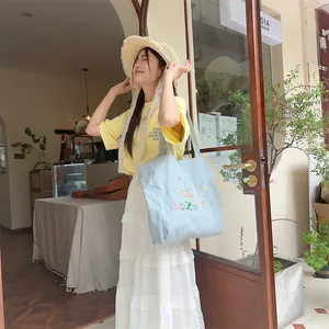 Gros plan sur un sac cabas en toile brodé bleu clair avec des motifs floraux d'été