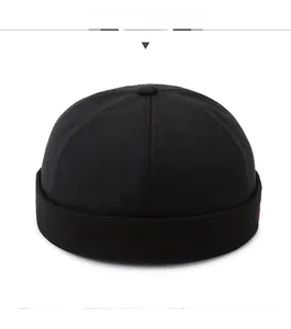 Close-up of black cotton docker hat showing top button and embroidered red detail