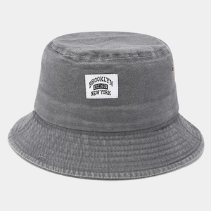 Detail of grey washed denim bucket hat featuring vintage Brooklyn woven patch and eyelets