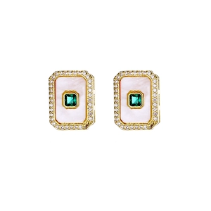 Detail view of rectangular white shell earrings with emerald center and zircon halo