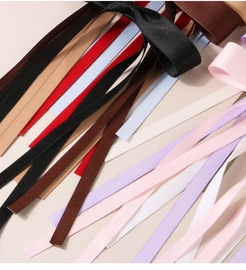 Detailed texture of colorful satin ribbon hair clips showing smooth fabric and soft bows
