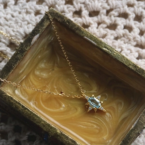 Macro shot of 925 silver star pendant with blue topaz and gold chain on marble