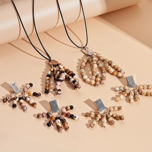 Bohemian style necklace featuring natural stone beads and tassel pendant on a beige surface