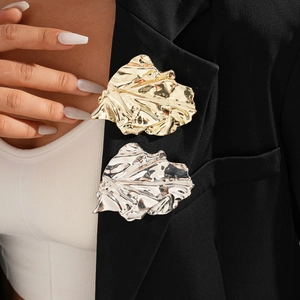 Irregular metallic pleated leaf brooch in gold and silver finish on black suit lapel