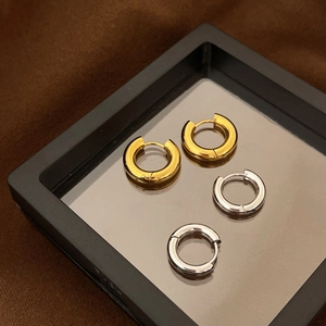 Detailed shot of polished gold and silver hoop earrings on a black frame display