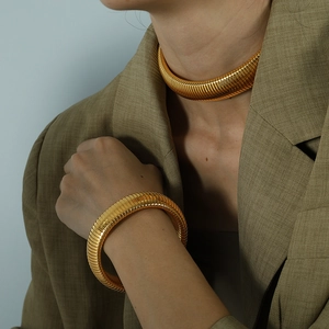 Chunky gold-plated ribbed stretch necklace and bracelet set worn with a khaki blazer