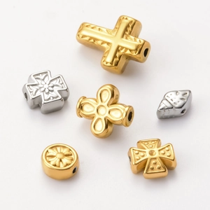 Detailed macro view of assorted gold and silver stainless steel cross and flower charm beads