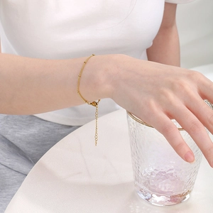 Detail of a minimalist gold satellite bead chain bracelet with adjustable extender on wrist