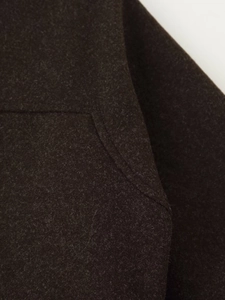 Macro shot of dark brown wool coat showing high-quality texture and stitching details