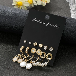 Detail view of 9 pairs gold earring set featuring faux pearls, hearts and rhinestones