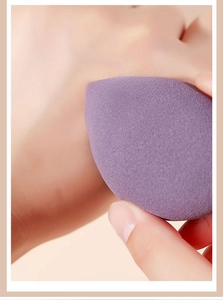 Close-up of soft purple makeup sponge being pressed to show high elasticity and texture