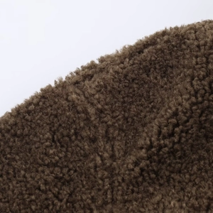 Close-up of soft dark brown faux shearling fabric texture with thick curly fibers