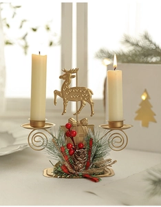 Close-up of golden reindeer iron double candle holder with festive pine and ribbon decor