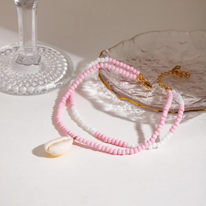 Close-up of double-layer beaded anklet with pink and white beads and a shell pendant