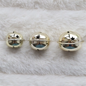 Three gold metal bells with star cutouts in various sizes on white plush fabric
