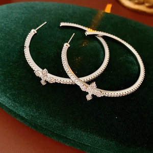 Macro shot of silver hoop earrings with cross pendants and zircon on green velvet