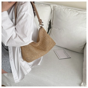 Detail of woven straw tote bag with brown leather shoulder strap and knot decoration