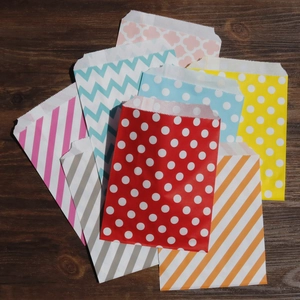 Sacchetti regalo colorati con motivi a pois e onde su sfondo in legno scuro