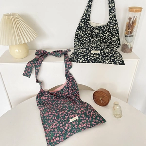 Détail du sac cabas en toile fleurie avec un grand nœud décoratif et l'étiquette Suzakka