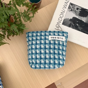 Détail de la pochette en tissu à carreaux bleus avec fermeture éclair et étiquette