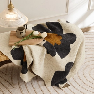 Nordic knitted blanket with caramel flower patterns on a beige plush sofa cover