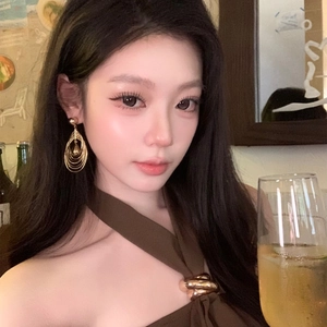 Detailed view of layered gold circular dangle earrings worn with a halter top outfit