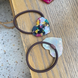 Close-up of elastic hair ties featuring colorful resin hearts and sparkling rhinestones