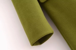 Dettaglio del polsino di un cappotto di lana verde oliva con trama del tessuto