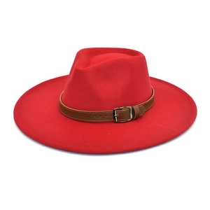 Détail d'un chapeau en laine rouge avec bande en cuir marron et boucle en métal argenté