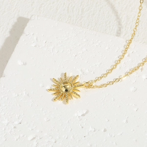 Elegant 14K gold-plated sunburst pendant necklace on a minimalist white stone base