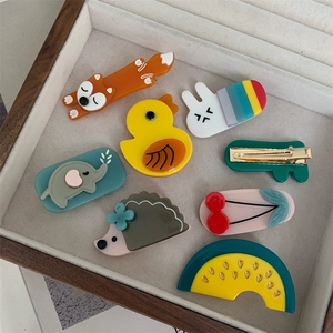 Detailed close-up showing the metallic spring clips on the back of cartoon acetate hairpins