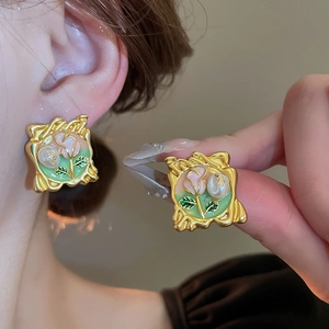 Detail of vintage French gold-plated floral earrings with pearls and green enamel