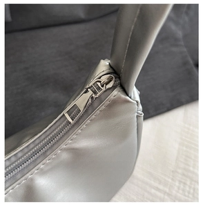 Detailed close-up of smooth zipper and precise stitching on silver moon-shaped shoulder bag