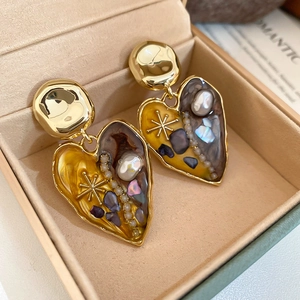 Detail of vintage heart earrings with freshwater pearls and colorful stones in a jewelry box