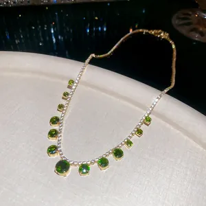 Elegant gold necklace with circular green emerald pendant and gradient tassel detail
